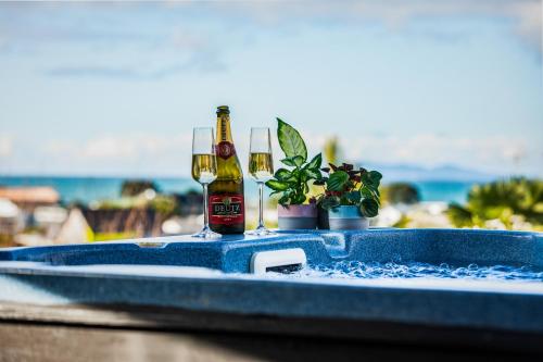 two bottles of beer sitting on a table with plants at Two Palms - Waihi Beach Holiday Apartment in Mangonui