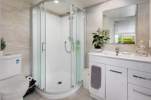 a bathroom with a shower and a toilet and a sink at Two Palms - Waihi Beach Holiday Apartment in Mangonui