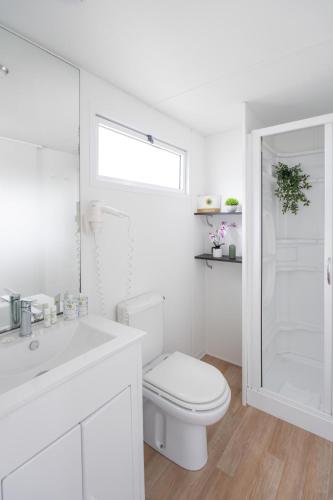 a white bathroom with a toilet and a sink at Club del Sole Jesolo Family Resort in Lido di Jesolo
