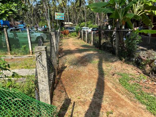 a fence on a dirt road next to a street at My Dream Resort in Canacona
