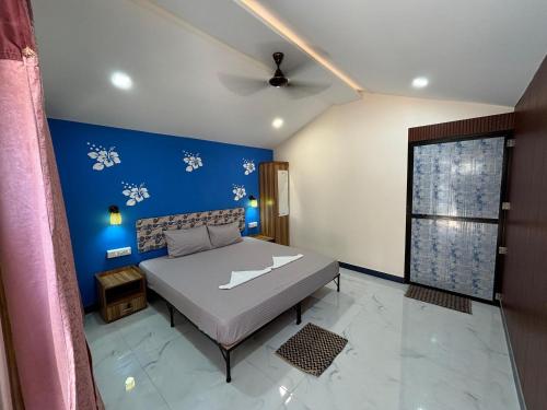 a bedroom with a bed and a blue wall at My Dream Resort in Canacona
