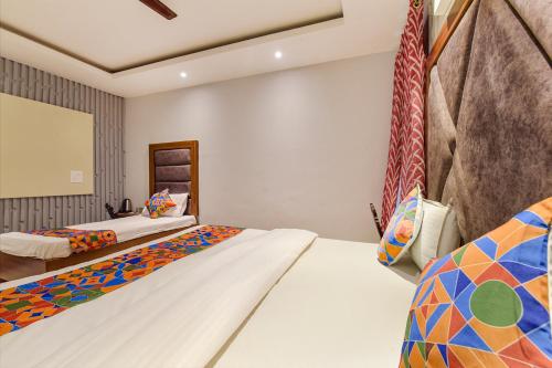 a bedroom with two beds and a mirror at FabHotel Prem Bihari in Haridwār