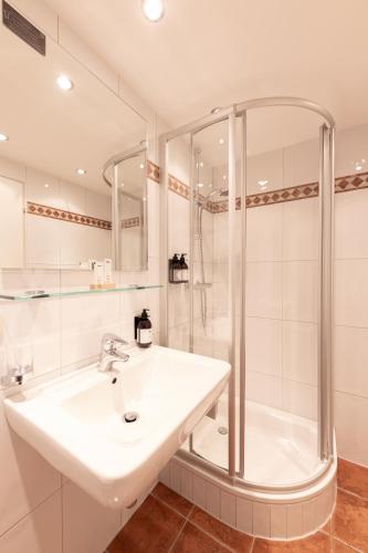a white bathroom with a sink and a shower at Quality Hosts Arlberg - Hotel Bergheim in Sankt Anton am Arlberg