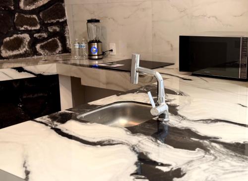 a kitchen sink with a marble counter top with a sink at Mansionality Lofts Hotel in Tlalpujahua de Rayón