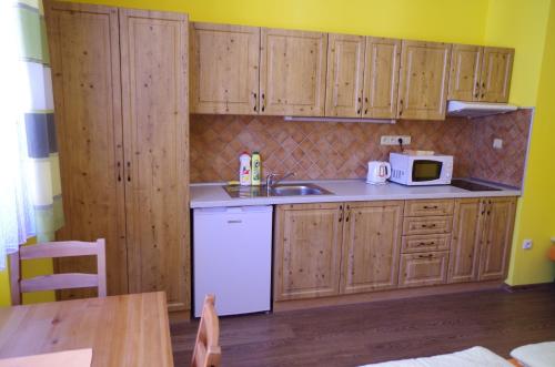 a kitchen with wooden cabinets and a white refrigerator at Ubytování a apartmány Sluníčko in Lomnice nad Lužnicí