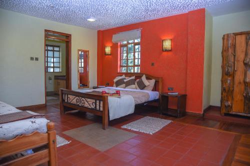 a bedroom with a bed and a red wall at Sangare Gardens- Book Now Enjoy Free Farm Tour in Mweiga
