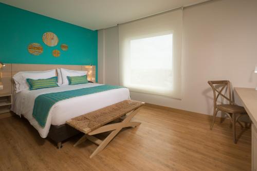 a bedroom with a bed and a desk and a window at bh Barranquilla in Barranquilla