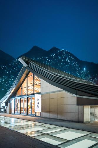 a building at night with mountains in the background at 清澜居 东方唐韵民宿酒店 in Xi'an