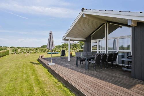 a wooden deck with a table and an umbrella at Lovely Summer House In Haderslev in Haderslev