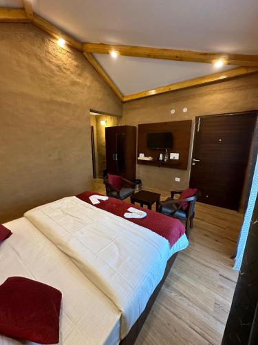 a hotel room with a large bed and chairs at Maatidera Resort Kanatal The Boutique stay in the Lap of Himalayas in Kanatal