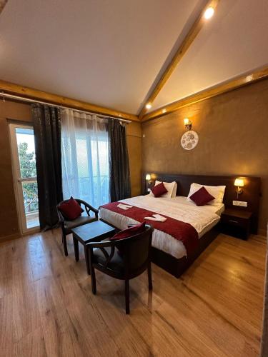 a bedroom with a bed and a table and a window at Maatidera Resort Kanatal The Boutique stay in the Lap of Himalayas in Kanatal