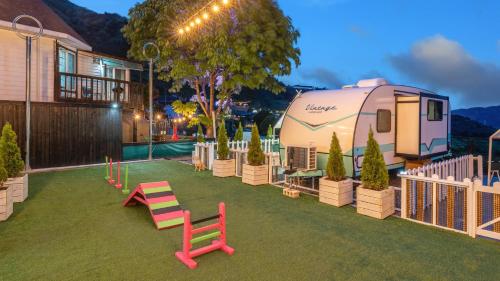 an rv parked in a yard next to a fence at Gapyeong Dongban84 Glamping&Pool villa in Gapyeong