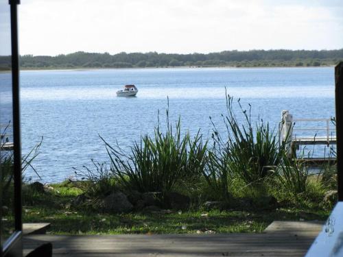 a small boat on the water with a dock at Beachfront Seagulls on Shoalhaven in Shoalhaven Heads
