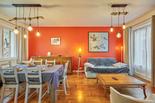 - un salon avec des murs orange, une table et des chaises dans l'établissement Gîte des Mascarets - Appt pour 4, à Pont-Audemer