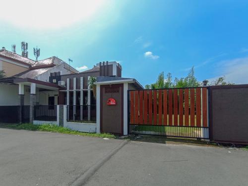 a house with a red gate and a fence at RedDoorz at Wisma Garden Purwokerto in Purwokerto