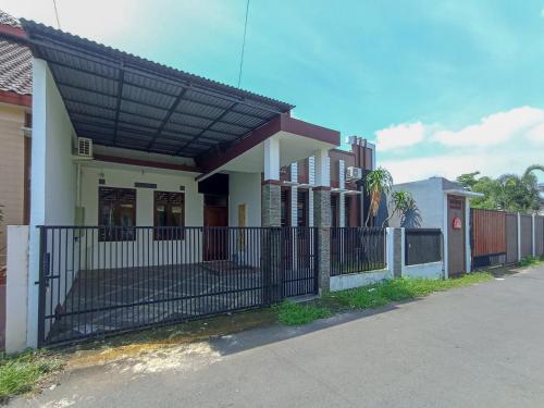 a house with a black roof and a fence at RedDoorz at Wisma Garden Purwokerto in Purwokerto