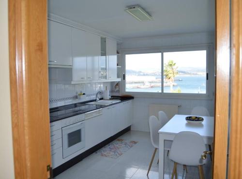 a white kitchen with a table and a window at Acogedor piso con vistas en Sada in Sada