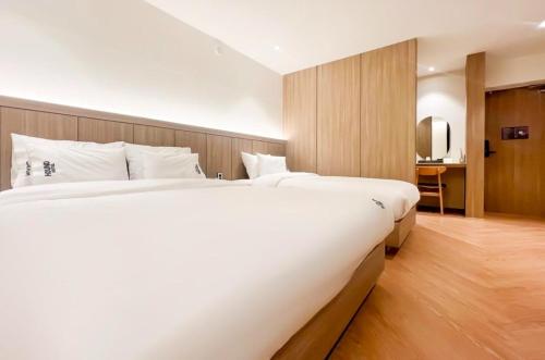 a hotel room with two beds and a television at Hound Hotel Jeonju Deokjin in Jeonju