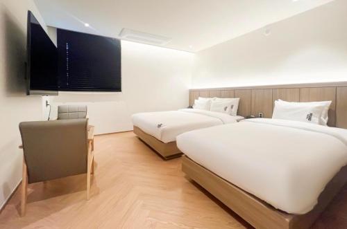 a bedroom with two beds and a flat screen tv at Hound Hotel Jeonju Deokjin in Jeonju