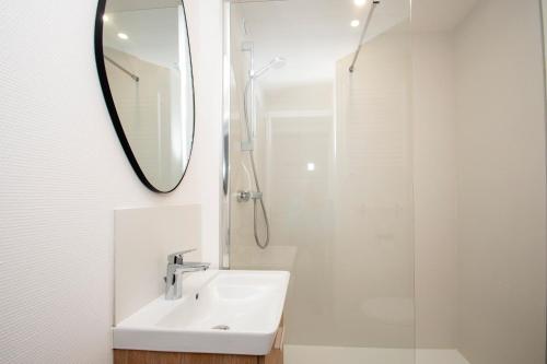 une salle de bain blanche avec un lavabo et un miroir dans l'établissement La Maëlea - Appt à Saint-Lary-Soulan pour 5, à Saint-Lary-Soulan