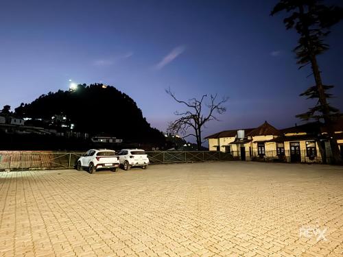 two white cars parked in a parking lot at Hotel Sunny Cot - Free Mall Shuttle and Parking in Mussoorie