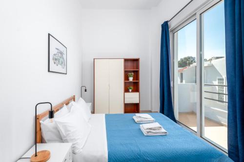 een slaapkamer met een bed en een groot raam bij Sea Apartment Ixia Ialisos in Ialyssos