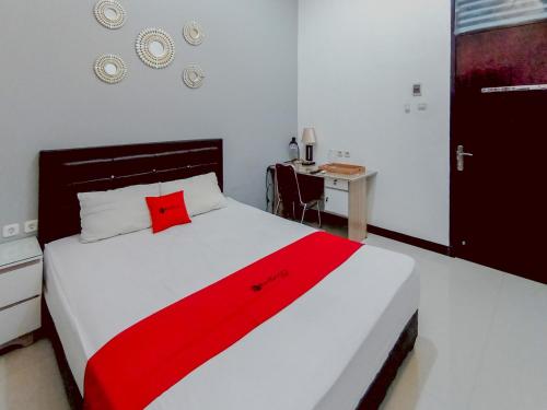 a bedroom with a large bed with a red blanket at RedDoorz at Wisma Garden Purwokerto in Purwokerto