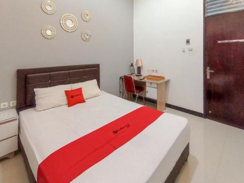a bedroom with a bed with a red blanket on it at RedDoorz at Wisma Garden Purwokerto in Purwokerto