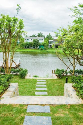 a stone path leading to a lake with trees at FLAMIGO ĐẠI LẢI RESORT - Villa View Hồ in Ngọc Quang