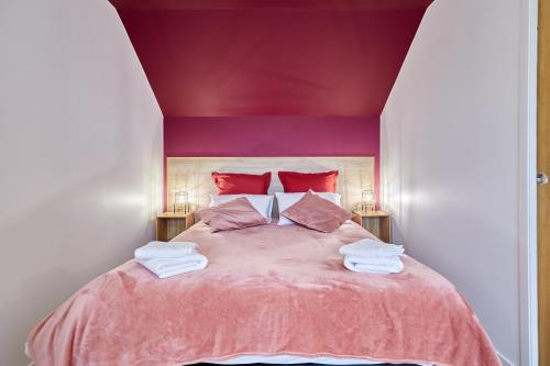 - une chambre avec un lit rose et des serviettes dans l'établissement Gîte de la Risle - Appt à 35 min de Deauville, à Pont-Audemer