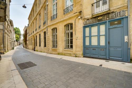 une rue vide devant un bâtiment avec une porte bleue dans l'établissement MDOR - Le Vendange - Plein coeur de Bordeaux, à Bordeaux
