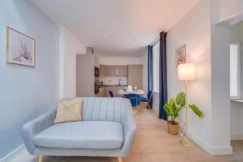 un salon avec une chaise bleue et une cuisine dans l'établissement MDOR - Le Tanin - En bail mobilité, à Bordeaux