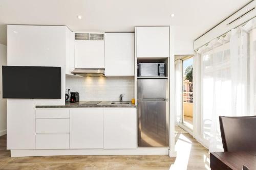 une cuisine avec des armoires blanches et un réfrigérateur en acier inoxydable dans l'établissement Monte carlo riviera 2, à Beausoleil