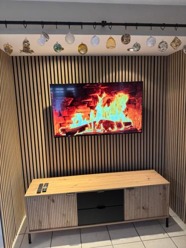 a flat screen tv on a wall with a bench at L Extension du Bonheur à Meisenthal in Meisenthal