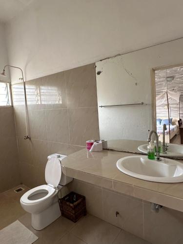 a bathroom with a sink and a toilet and a mirror at La Guesthouse Étoile in Cotonou