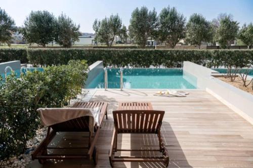 two chairs sitting on a deck next to a swimming pool at Cretan Dream Resort & Spa in Stalos