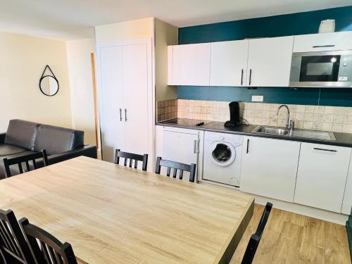 une cuisine avec des armoires blanches, une table et un évier dans l'établissement T3 au cœur du centre historique de Briançon #6, à Briançon