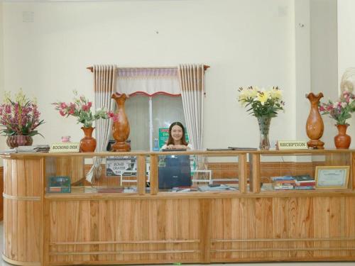 フォンニャにあるPhong Nha Riverview Homeの鏡を持ったカウンターの後ろに立つ女性