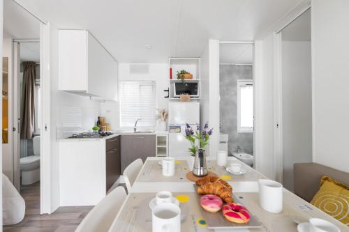a white kitchen with a table with food on it at Club del Sole Jesolo Family Resort in Lido di Jesolo