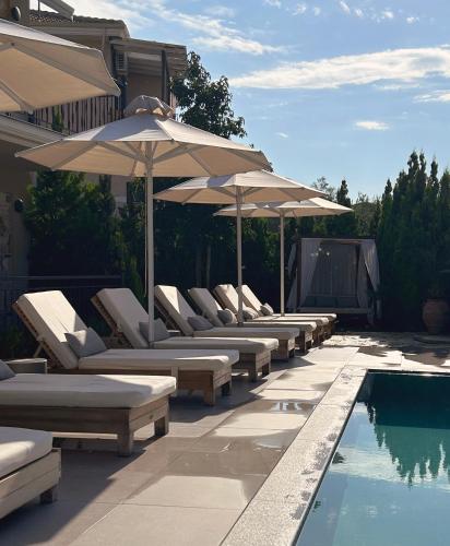 a row of lounge chairs and umbrellas next to a pool at Charisma Boutique Hotel in Parga