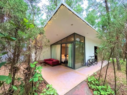 a house in the woods with a red couch on a patio at Villa Owner tại khu nghỉ dưỡng sinh thái Đại Lải Resort in Ngọc Quang