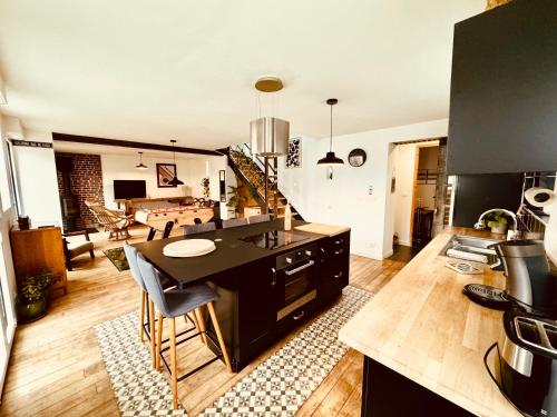une cuisine avec un îlot noir et un salon dans l'établissement Fermette cosy, Bain nordique & Baby foot, à Fromelles