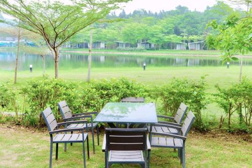 a table and chairs sitting next to a lake at FLAMIGO ĐẠI LẢI RESORT - Villa View Hồ in Ngọc Quang