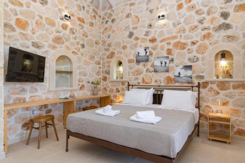 a bedroom with a bed and a stone wall at Villa Mezzo Suite by Villa Plus in Skinária