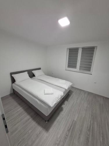 a white bedroom with a bed and two windows at Stan na dan Djogić in Nevesinje