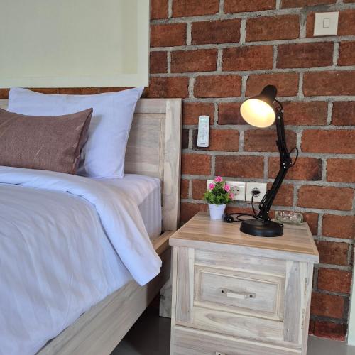 a bed with a lamp on a nightstand next to a brick wall at Rice Field inn - Lombok in Tetebatu