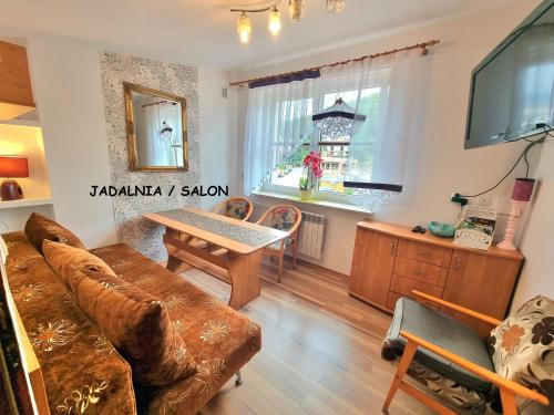 Apartament Kacperek samo centrum, Willowa 4A - 2 sypialnie, salon - dla rodziny 4-5 os في شتوروك: غرفة معيشة بها أريكة وطاولة ونافذة