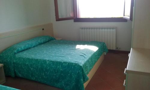 a bedroom with a bed with a green comforter at Agriresidence San Pietro in Bibione