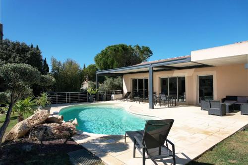 a swimming pool with chairs and a house at very pretty contemporary villa with pool located in Aureille in the alpilles, close to the center on foot. sleeps 4. in Aureille