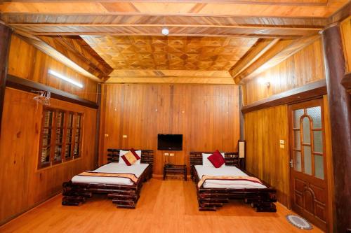 two beds in a room with wooden walls at Bai Tu Long Mountain Resort in Hà Cái